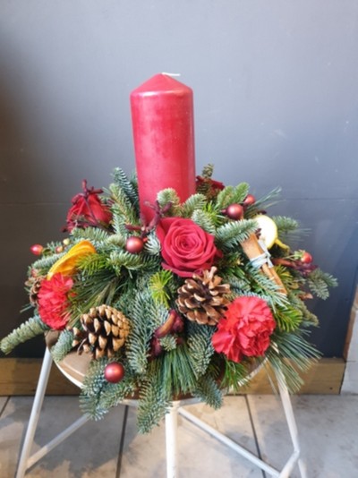 Red Pillar Candle in ceramic pot with Christmas foliages and decorations to include fresh flowers.