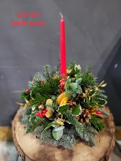 Classic round posy 10inch with winter foliages, holly, berries, pines and oranges with a single candle. Lovely Christmas token. Made by local independent florist delivering to Croydon, CR in Surrey, UK