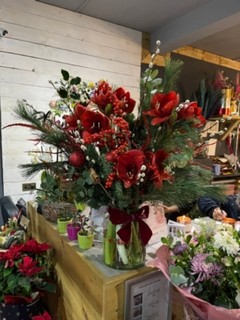 Amazing display of Amaryllis, twigs, Roses, Ilex in tall vase presented with Christmas foliages and scented Eucalyptus.  Definitely a wow factor centerpiece to be placed next to the fireplace or on the sideboard.  Made by independent florist in Croydon, Surrey, UK for guaranteed Christmas delivery 