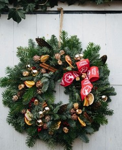 Natural door wreath Mary with pines, red bow, cinnamon stick, orange slices, feathers, blue pine.